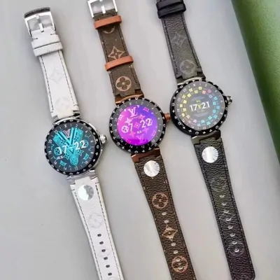 Three round smartwatches lying side by side on a pale surface, each with a lit colour screen and a bezel printed with hour markers. The leather straps are embossed with a repeating motif, in white, tan and dark grey.